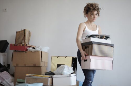 concentrated woman carrying stack of cardboard boxes for relocation