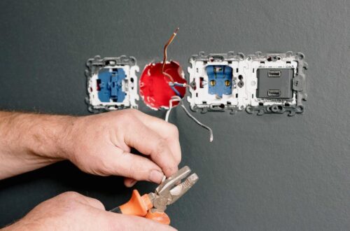 an electrician using pliers to repair the ac power plugs and sockets